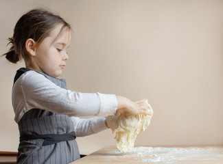 children's hands knead dough for home baking bread, pizza, pasta on the background of a wooden table. - Powered by Adobe