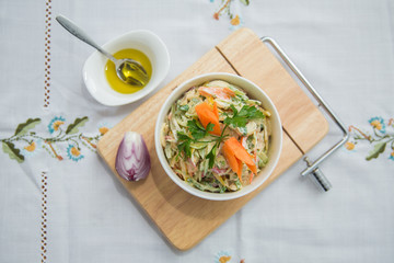 Chopped red onion . olives on a small white bowl . wooden board . Salad with ham, red and orange pepper, mushrooms, pickles, white sauce, on a white bowl and olives.