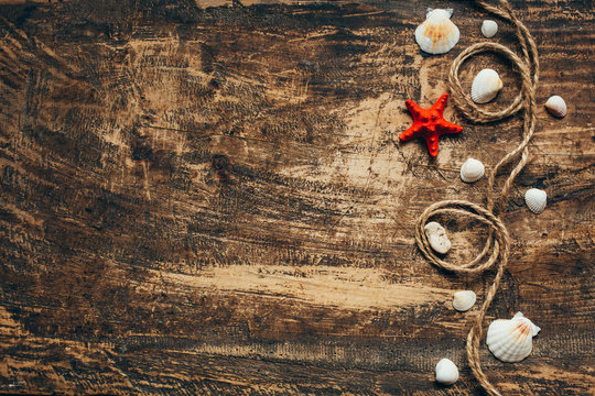 Concept of the summer time with fishstar and sea shells on the wooden blue background.