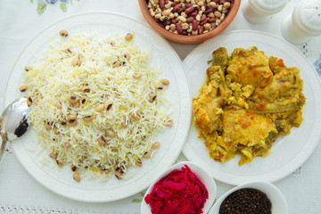 Khan pilaf in a pita . Dry beans on top of pilaf . Dry beans in a brown bowl . Chicken curry on the white plate . red cabbage sauerkraut and black pepper in a small bowl . Shah pilaf on the plate.