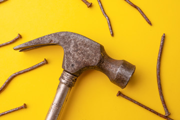 Old hammer and rusty nails. Yellow background. From abo