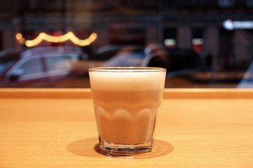 Cappuccino in a glass cup against the backdrop of the city.