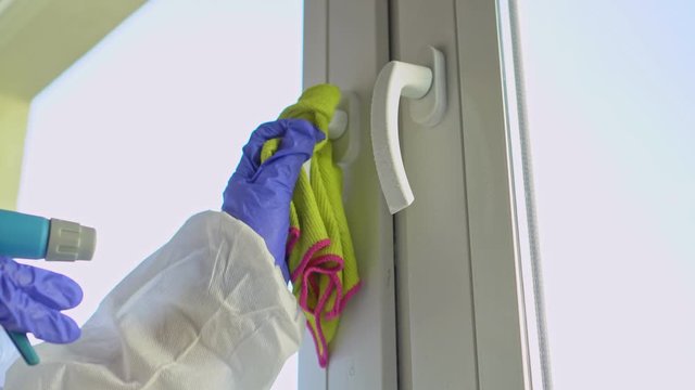 Hand in protective glove with rag cleaning door handle.