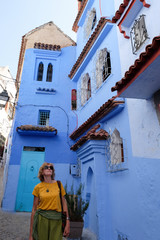 Middle-aged pretty female tourist traveling in the kasbah - old part of city Chefchaouen, Morocco.