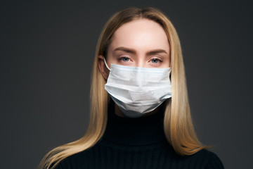 Young girl in a medical mask. Isolated on grey background. Health care and medical concept. Close up portrait.