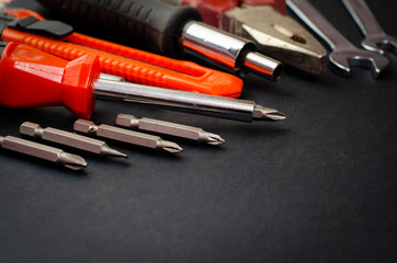 A Set of a lot of different red tools for working include hammer wrench bit pliers, screwdriver,  paper knife, screwdriver nozzle, key on black background 
