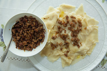 Roasted meat in a bowl . A bowl of white ceramic salt and pepper . Traditional azerbaijani khingal...