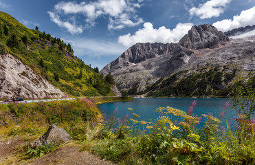 Naklejka na ściany i meble Amazing natural scenery in Dolomites Alps. Summer view of Fedaia lake and Marmolada mountain. Picture of wild area. Awesome alpine highland in sunny day