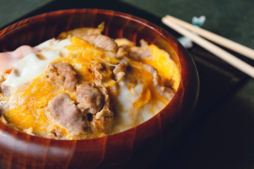 Baked Pork Rice with Eggs in a Wooden Bowl, Kitchen Tableware, Top View Green Wood Background with Natural Light by Morning Window, Japanese style food, Selective focus.