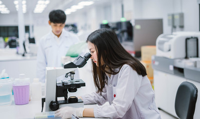 Two medical scientist working in Medical laboratory , young female scientist looking at microscope. select focus in young female scientist