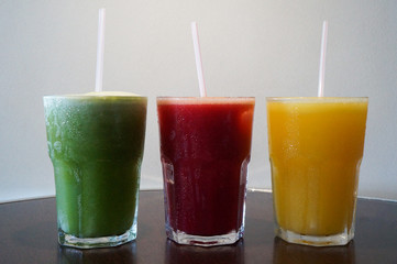 Healthy and colorful fruit juices. Green (pineapple with mint), red (apple, watermelon, strawberry) and yellow (orange, tangerine)
