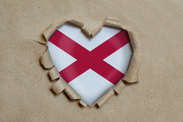 Heart shaped hole torn through paper, showing Alabama flag