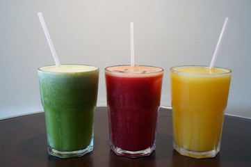 Healthy and colorful fruit juices. Green (pineapple with mint), red (apple, watermelon, strawberry) and yellow (orange, tangerine)