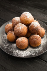 Homemade cottage cheese donuts on the black plate on the  dark  wooden background. Location vertical. Closeup.