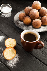 Black coffee and homemade cottage cheese donuts on the  dark  wooden background. Location vertical. Closeup.