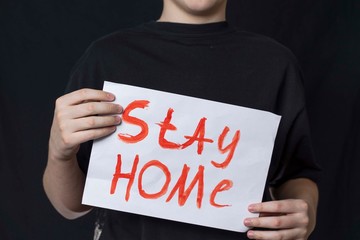 a teenager in a black T-shirt stands with the inscription stay home