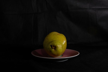 a juicy pear is lying on a pastel pink saucer