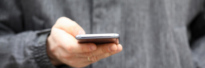 Closeup man in jacket holds smartphone his hands