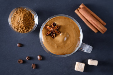 Whipped dalgona coffee with spices on a dark background. Korean coffee drink. Flat lay composition