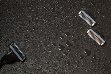 Male shaving machine on a black stone surface in drops of water.