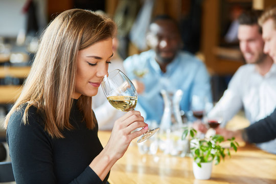 Young woman smells a glass of white wine