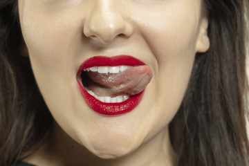 Smiling girl opening her mouth and showing the long big giant tongue isolated on white background. Looks shocked, attracted, wondered and astonished. Copyspace for ad. Human emotions, marketing.