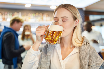 Young woman takes a big sip of beer