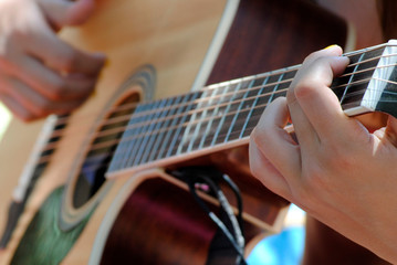 Fototapeta premium Hands of a young woman playing a Spanish guitar closeup.