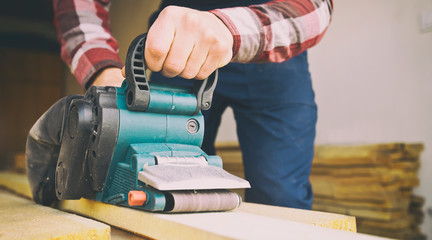 The carpenter process the wood by the belt sander