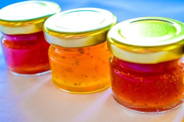 pineapple, orange and strawberry jams in the small glass bottle