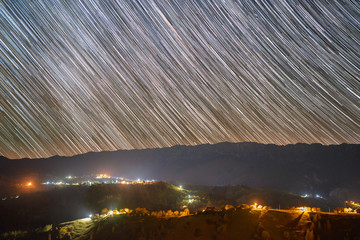 Star trails over the Pestera village in Piatra Craiului mountains from Romania