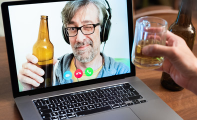 Video call between friends, distant relatives, middle-aged man toasts with beer together with another person using modern communication technologies
