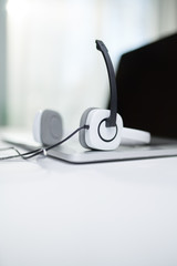 Laptop with black screen, headphones, microphone on table on bokeh background.
