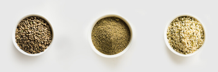 Organic dried hemp seeds, flour, kernels in white bowls isolated on white. View from above.