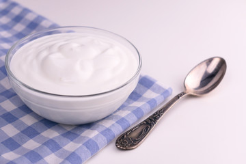 Fototapeta na wymiar Greek yogurt in a glass bowl on a white table. Copy space.