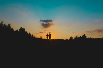 Naklejka premium Silhouette of happy boy and girl run at sunset