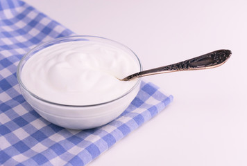 
Greek yogurt in a glass bowl on a white table. Copy space.