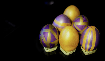 Purple golden Easter eggs on a black background