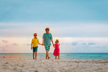 father with son and daugther walking on beach