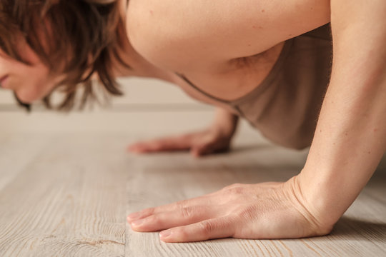 Woman doing push-ups exercise on hands or practicing yoga at home. Close-up of hands. Body positive trend.