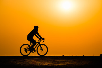 Fototapeta premium Silhouette man cycling on sunset background