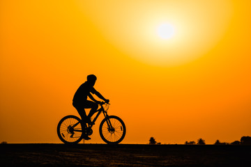 Obraz na płótnie Canvas Silhouette man cycling on sunset background