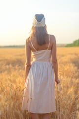 Back view woman with long hair in field at sunset unrecognizable