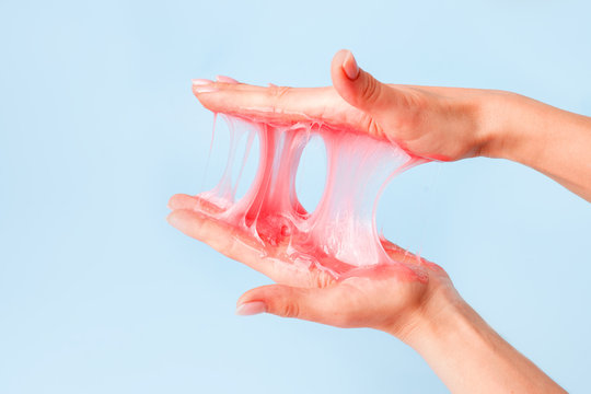 ASMR Young girl hands with sticky purple slime on blue background, liquid wax for depilation, conceptual flyer banner with copy space, antistress relax, modern kids hobby