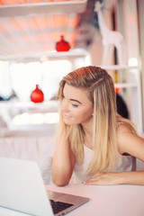 a young smiling businesswoman is working  on a laptop in a cosy cafe 