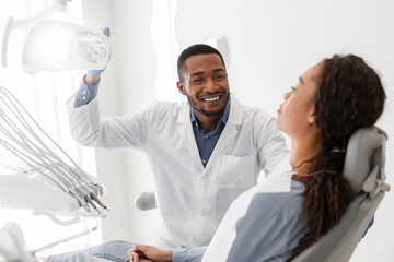 Cheerful black dentist turning on equipment before check up
