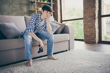 Photo of teenager school boy sit couch stay home quarantine time hold joystick playing video game addicted gamer loser waiting next set bored head on hand living room indoors - obrazy, fototapety, plakaty