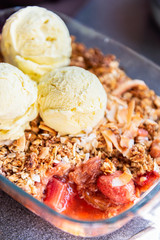 Home cooked Rhubarb and Strawberry crumble from oatmeal and nuts topping and with vanilla ice cream scoops