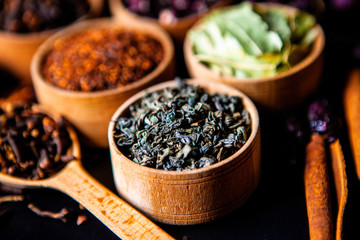Various dried tea leaves in wooden bowl. Dried herbs tea leaves close up. Different dry herbs and flowers for making healthy tea background.