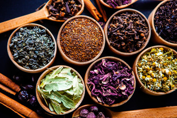 Various dried tea leaves in wooden bowl. Dried herbs tea leaves close up. Different dry herbs and flowers for making healthy tea background.
